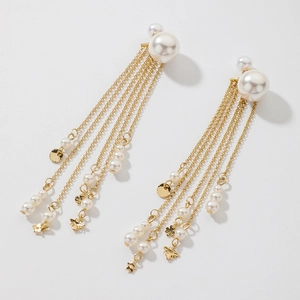 Detail view of long gold tassel earrings with imitation pearls and star pendants