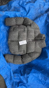 Detail shot of a grey knitted jacket featuring a tall collar and white product size tag