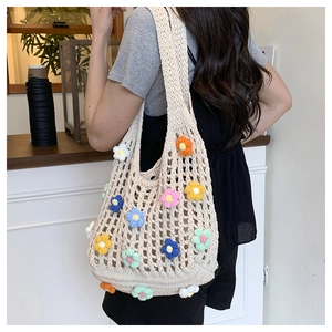 Detail of hollow knit tote bag with colorful 3D crochet flowers on creamy white texture