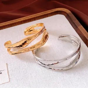 Bracciali aperti irregolari a doppio strato in oro e argento su un vassoio di velluto
