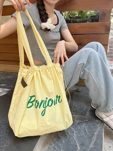 Yellow drawstring canvas tote bag with green Bonjour print for casual daily use