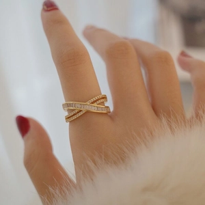 Détail d'une bague croisée dorée sertie de zircons portée par un mannequin