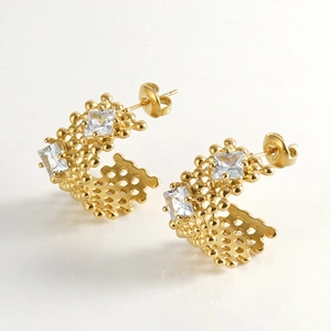 Detail of gold U-shaped earrings with square zircon inlay and delicate hollow metal beadwork