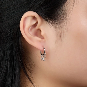 Close-up of S925 silver earrings with star, moon, and cross pendants on a model