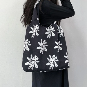 Detail of black canvas tote bag with white floral sunburst print on shoulder
