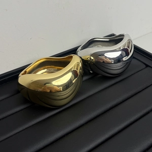 Detail von breiten Metall-Armreifen in Gold und Silber mit unregelmäßigem Wellen-Design