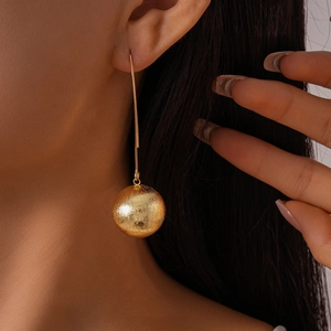 Detailed close-up of a long golden metallic ear hook with a textured spherical pendant