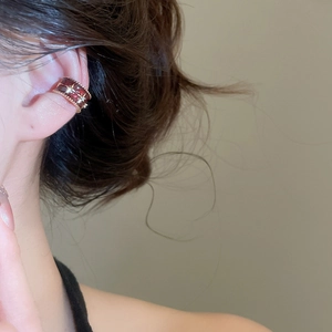Close-up of a red gold bow ear cuff with zircon inlay on a female model's ear