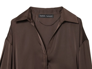 Détail de la texture satinée et du col marron avec étiquette de marque et de taille