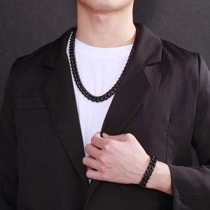 Men's black stainless steel Cuban necklace and bracelet set worn by a model in a suit