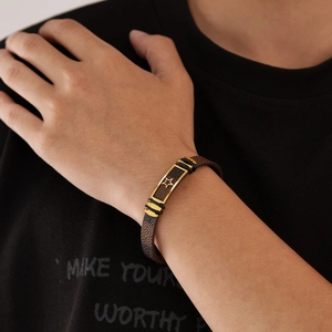 Brown leather bracelet for men featuring a gold star charm and black buckle on wrist