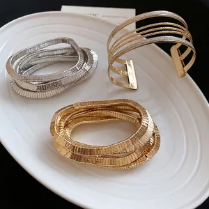 Mixed metal stacked open cuff and spiral bracelets in gold and silver finish