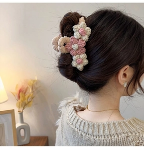 Detail of hand-knitted flower hair claw with three soft wool blooms for hair styling