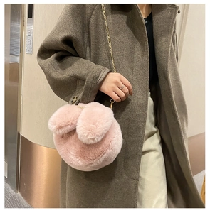 Pink plush bunny bag with long ears and gold chain strap shown on a model