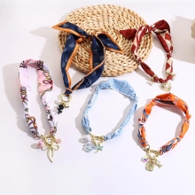 Flat lay detail of assorted patterned pet collars with gold metal buckles and charms