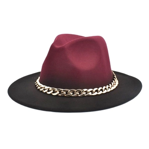 Detail of burgundy fedora hat with black wide brim and chunky gold chain accessory
