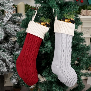 Classic knitted Christmas stockings in red and grey with cable pattern on a festive tree