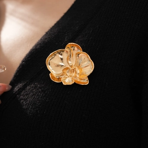 Detailed macro view of the golden orchid brooch pinned on a black knitted sweater