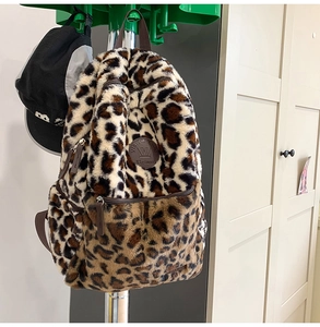 Dettaglio dello zaino in peluche leopardato con trama morbida e stemma tondo decorativo