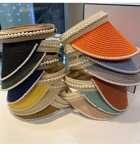Detail of straw sun hats with pearl trim showing diverse colors and braided texture
