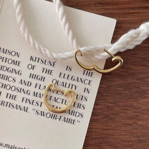 Close-up of elegant gold heart-shaped earrings on a stylish cream card with wood background