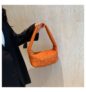 Macro shot of orange shoulder bag with quilted floral texture and 3D puffy pattern