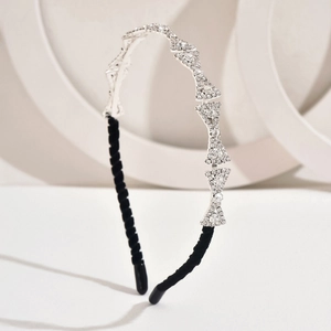Detail of silver rhinestone bow headband wrapped in elegant black velvet fabric
