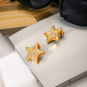Detailed shot of gold star stud earrings with sparkling crystals on a silver laptop surface