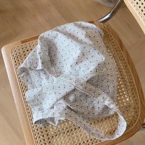 Gros plan détaillé du sac cabas en coton fleuri sur une chaise en rotin vintage