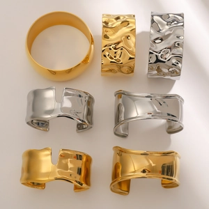 Detailed view of various minimalist wide open cuff bracelets in gold and silver finishes