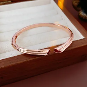 Elegant rose gold open bangle with liquid metal wave design in a premium jewelry gift box