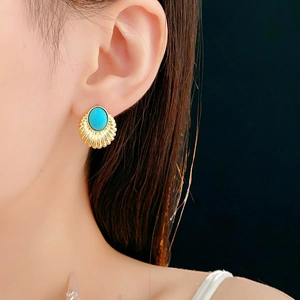 Detail of vintage gold fan earrings with oval teal gemstone on model for style
