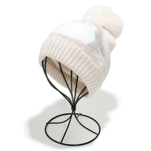 Detail of color-block knit hat with ribbed cuff and large plush faux fur pom pom