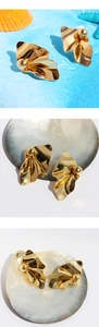 Macro shot of gold wrinkled metal earrings with a textured geometric wave pattern