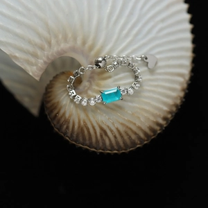 Macro detail of adjustable silver ring with sea blue stone inside a white seashell