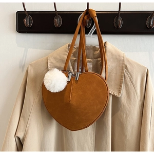Details der herzförmigen braunen Wildledertasche mit weißem Pompon und Silberreißverschluss