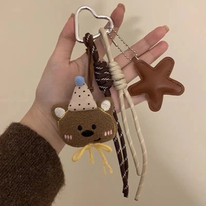Dettaglio di orsetto di peluche con ciondolo a stella in pelle e corda intrecciata chic