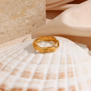 Macro shot of 18K gold plated stainless steel wave ring placed on a white seashell