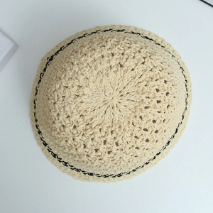 Detailed top view of beige straw bucket hat featuring black contrast woven stitch detail