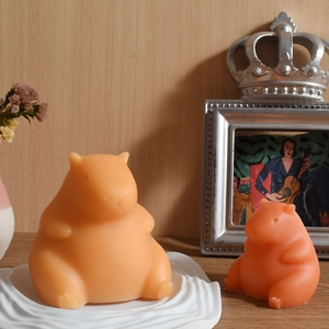 Detail of two cute capybara shaped candles on a wooden table with vintage decor