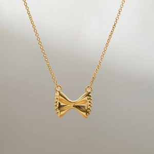 Close-up of golden sun bow pendant with glossy metallic finish on a fine chain