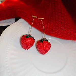 Macro de boucles d'oreilles fraise 3D étincelantes avec strass rouges sur assiette blanche