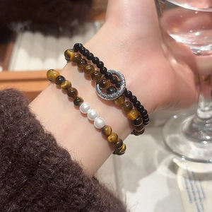 Detailed close-up of tiger eye and pearl beaded bracelet set with vintage silver clasp