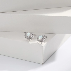 Detail view of silver sunburst stud earrings with white opal center on a white pedestal