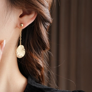 Gros plan de boucles d'oreilles asymétriques plaquées or 18k serties de cristaux