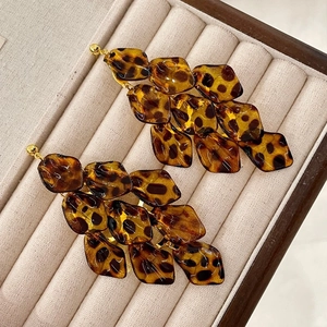 Retro acrylic leopard print petal tassel earrings with gold posts on beige velvet tray