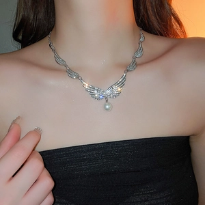 Detail of silver wing necklace with sparkling zircons and a white pearl on a model