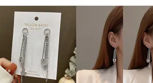 Detail of silver safety pin earrings with dangling star chains on an Asian model