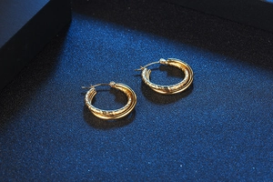 Detail of interlocking gold double hoop earrings with smooth and hammered metal textures