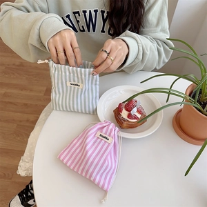 Detail of striped cotton drawstring pouches in green and pink for travel storage